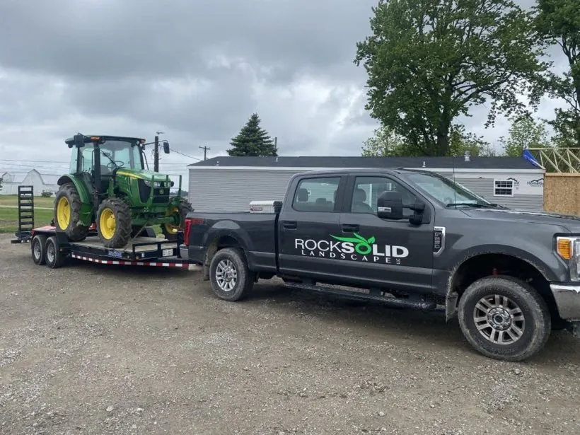 Rock Solid Landscape truck hauling a tractor